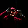 A spooky illuminated mask figure with a red hoodie in a dark setting, perfect for Halloween themes.